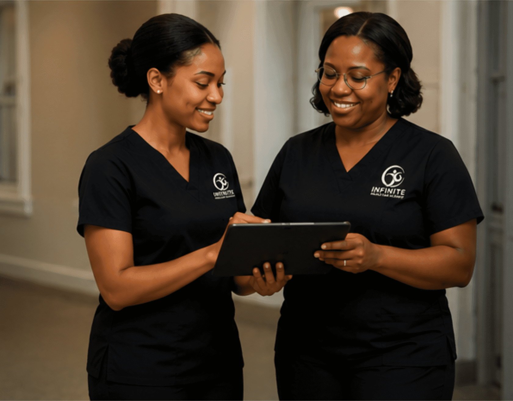 Two healthcare workers in scrubs using tablet