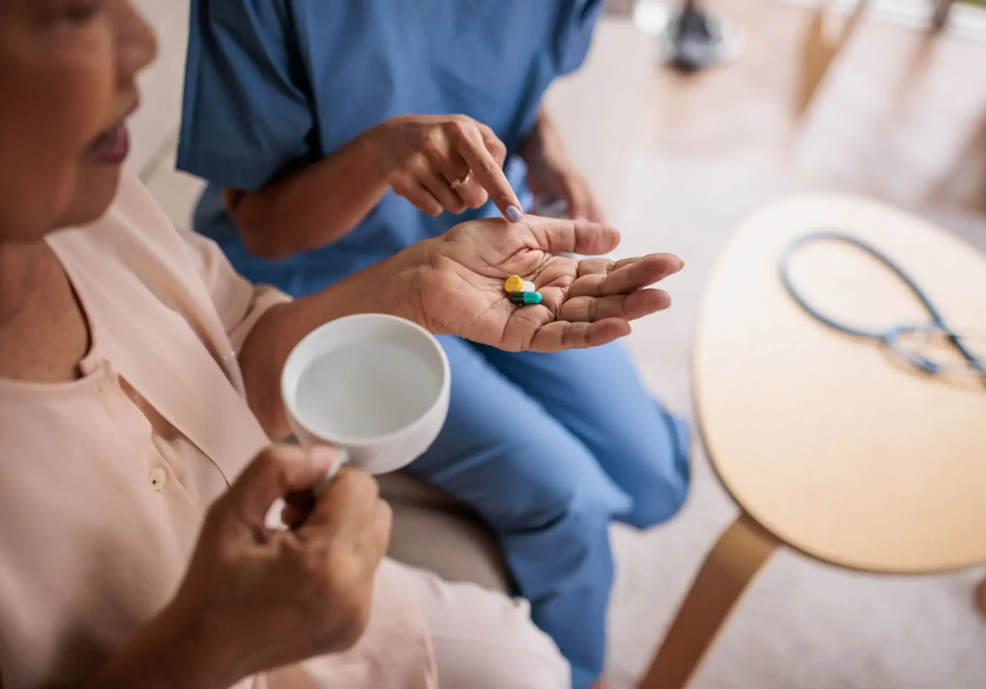 Caregiver handing pills to elderly patient