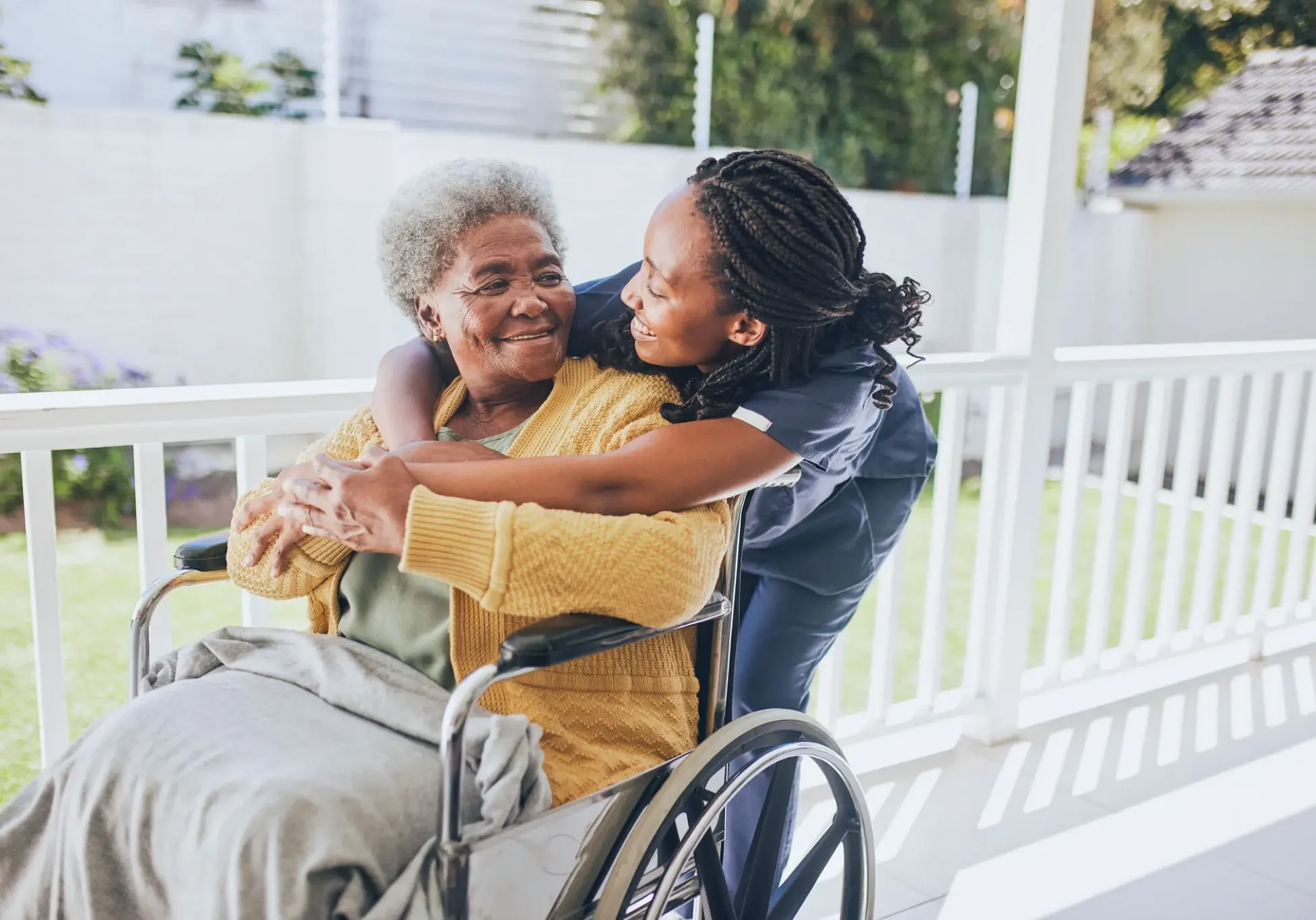 Caregiver hugging elderly woman in wheelchair