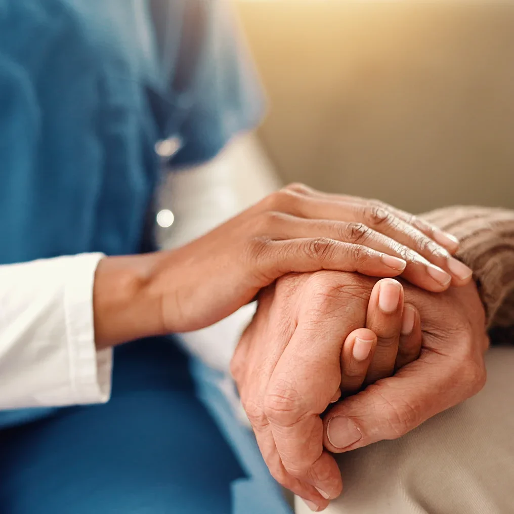 Healthcare worker holding elderly patient's hands