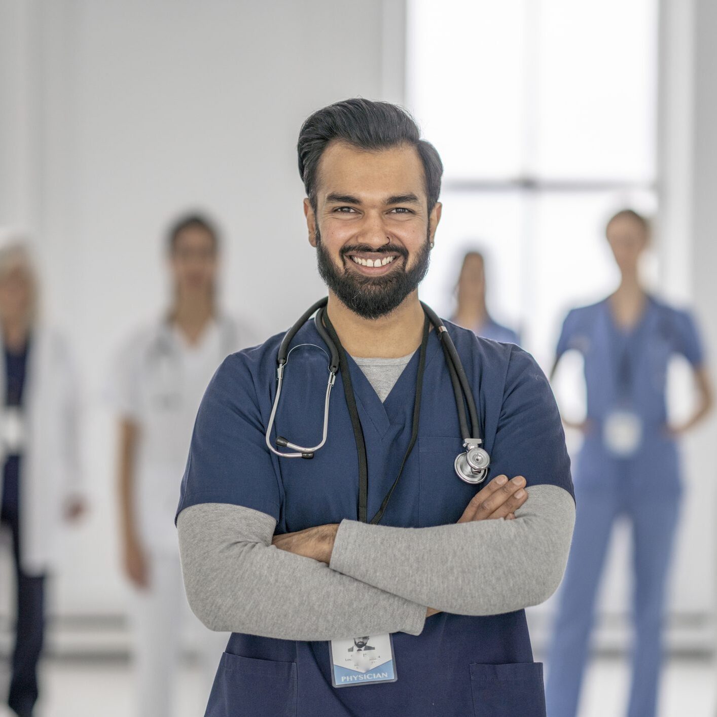 Smiling male doctor with healthcare team behind